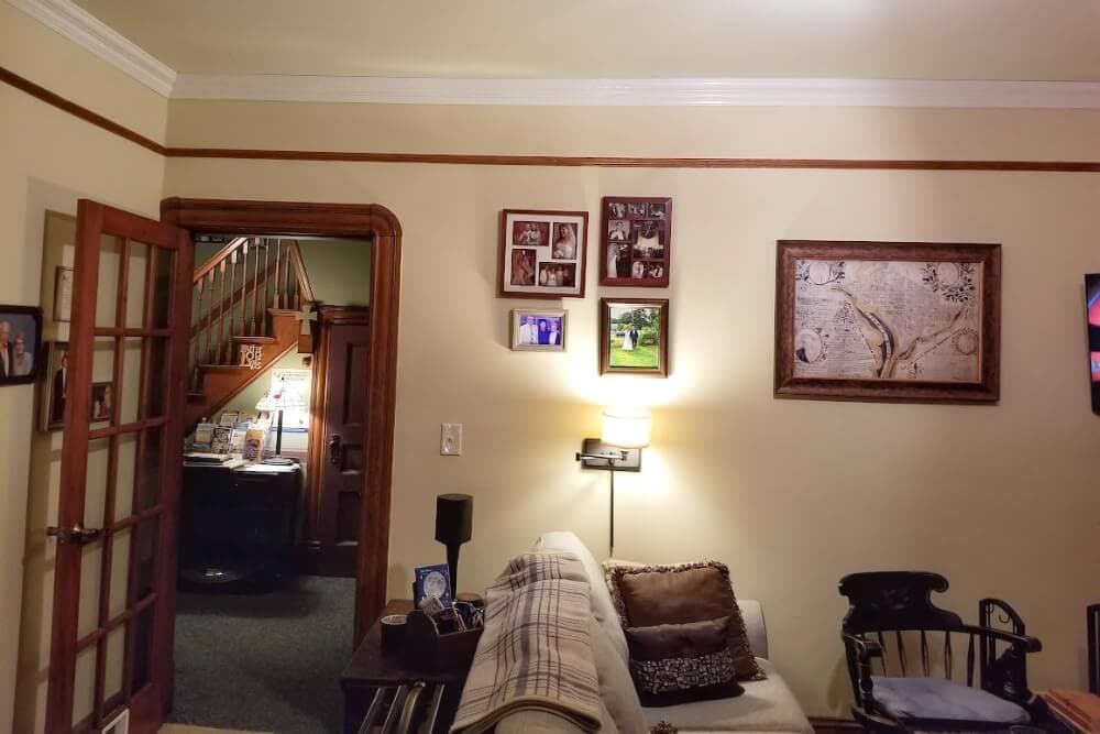 Cozy living room with a couch, decorative wall art, and an open doorway leading to a staircase.
