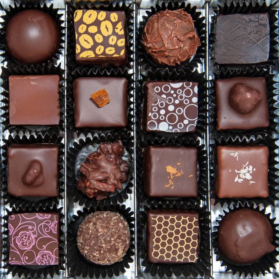 An assorted box of chocolates featuring various shapes, patterns, and textures.