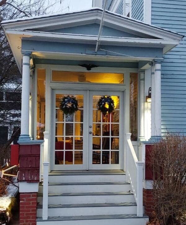 Front entrance of a house featuring double doors adorned with wreaths.