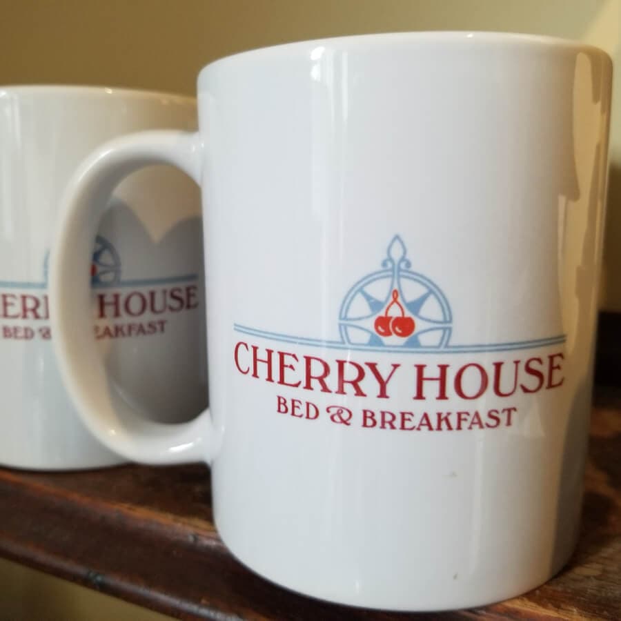 White coffee mugs featuring the "Cherry House Bed & Breakfast" logo.
