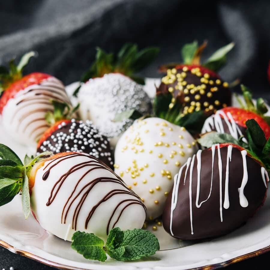 A plate of chocolate-covered strawberries decorated with various toppings.