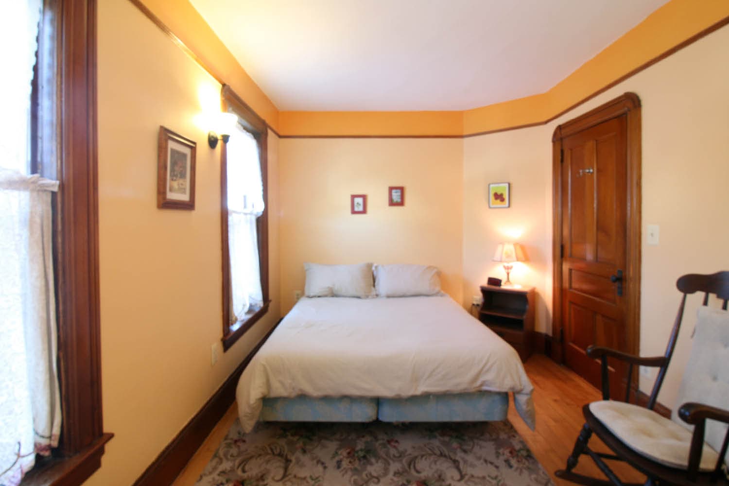 Cozy bedroom with a double bed, wooden furniture, and warm yellow walls.