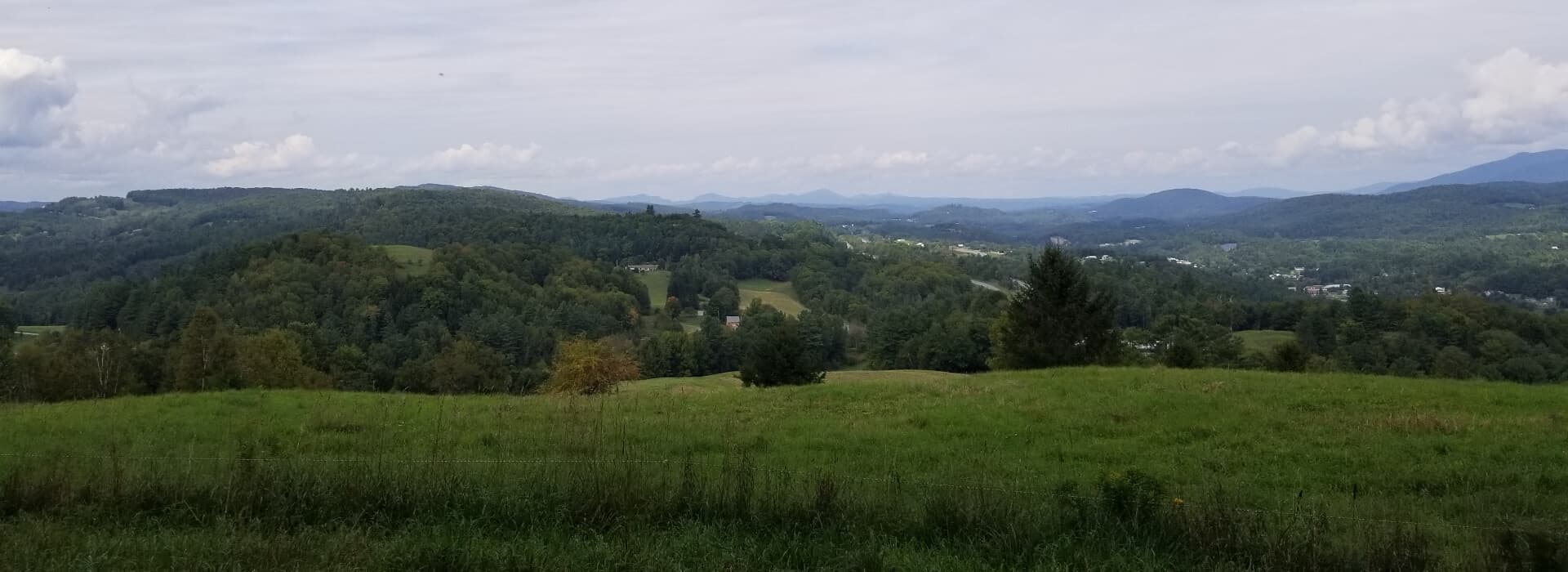 A panoramic view of rolling green hills under a cloudy sky.